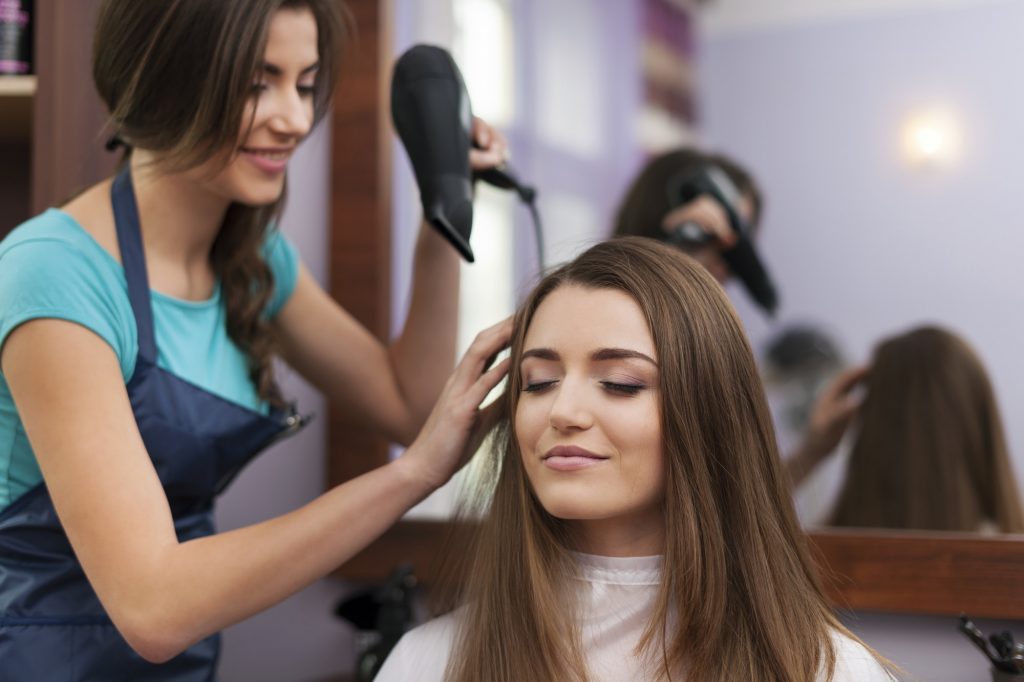 Hair stylist drying woman's hair