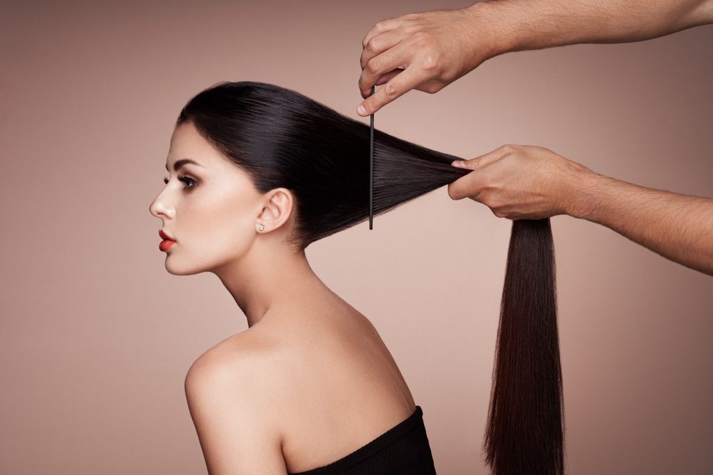 Hairdresser combs the hair of a woman