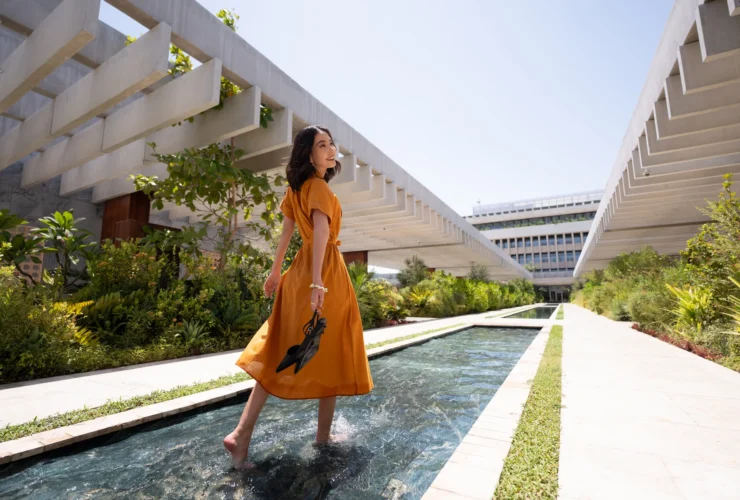 The Ned Doha garden pool exterior with woman in orange dress