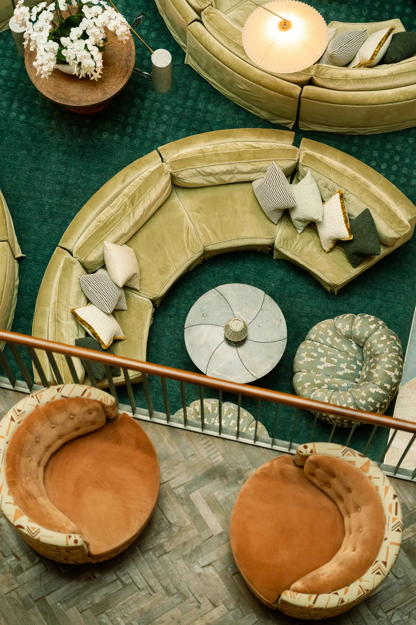 An overhead view of The Ned Doha lounge with sculptural sofas on deep green carpet