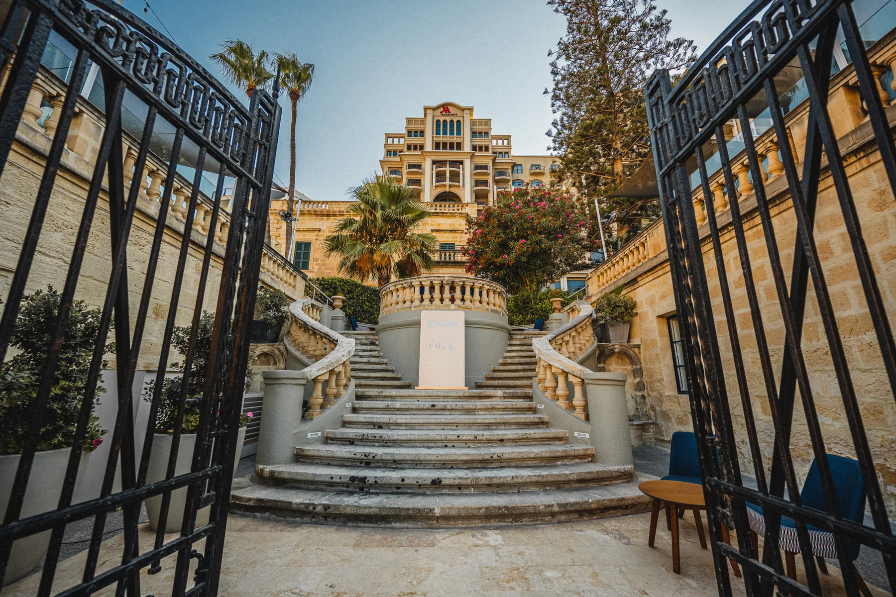 A wrought-iron gate at The Xara Palace looking down stone steps into Mdina