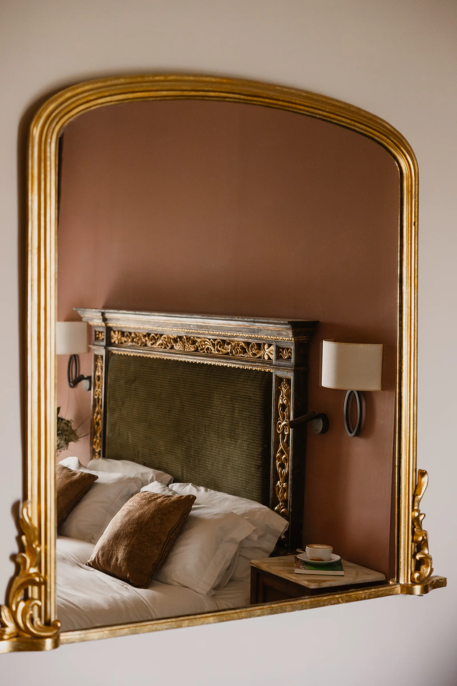 A guest room at The Xara Palace with mauve walls and a gilded mirror