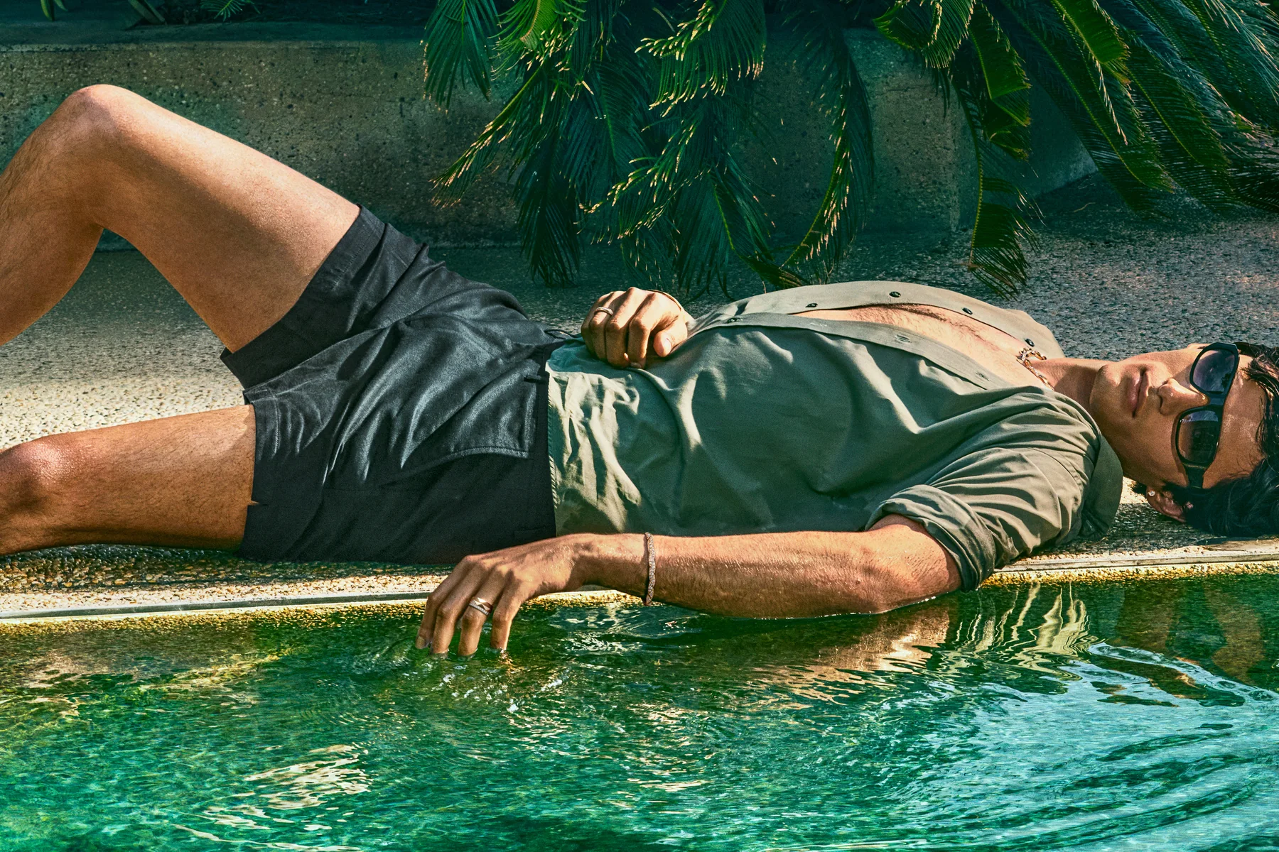 Model Akbar Shamji by the pool wearing a Laurence Graff Signature gold bracelet at the Sheats-Goldstein Residence