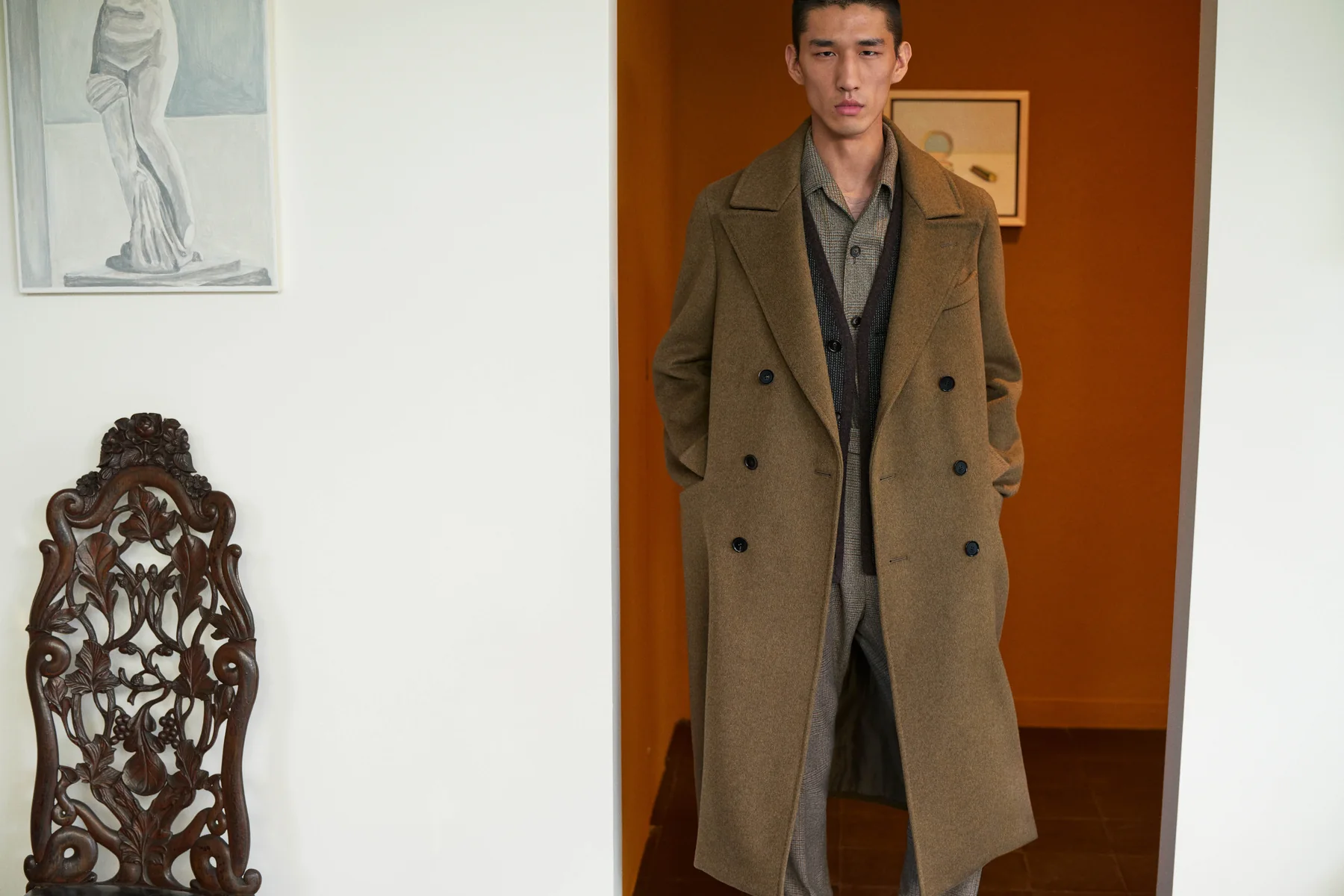 A model in a long brown Loro Piana coat in a doorway, Fall Winter 2026-2027 campaign by Mario Sorrenti