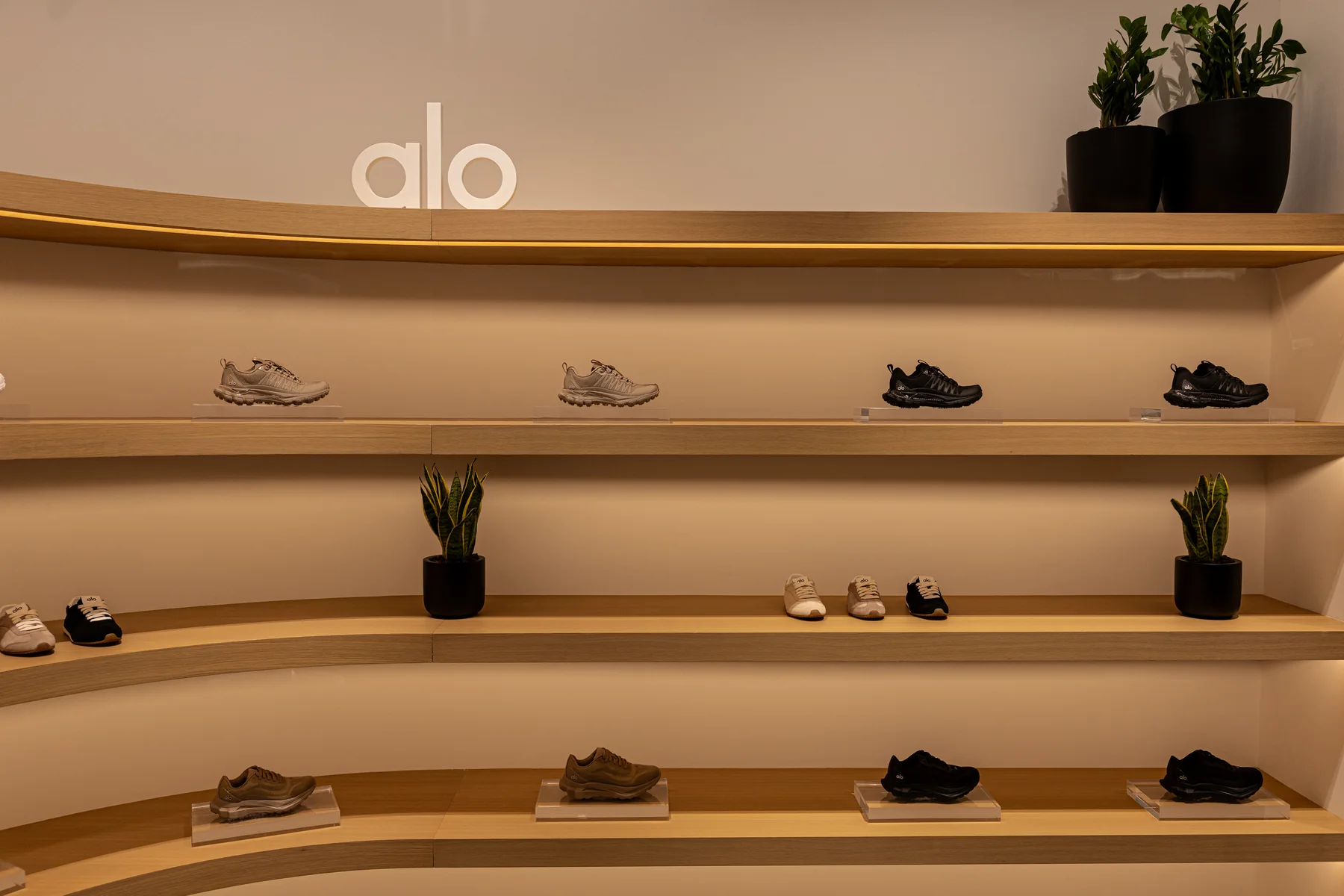 ALO footwear and accessories on curved wood shelving
