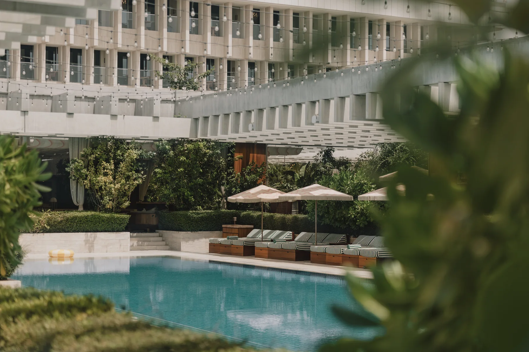 The garden pool at The Ned Doha set beneath the hotel colonnaded facade