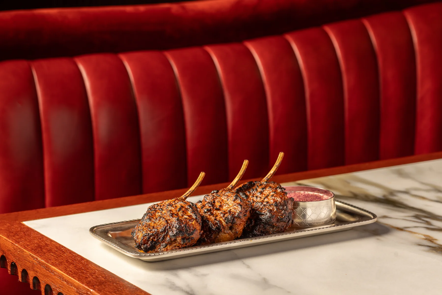 Tandoori masala lamb chops against the red banquette at Gymkhana Dubai