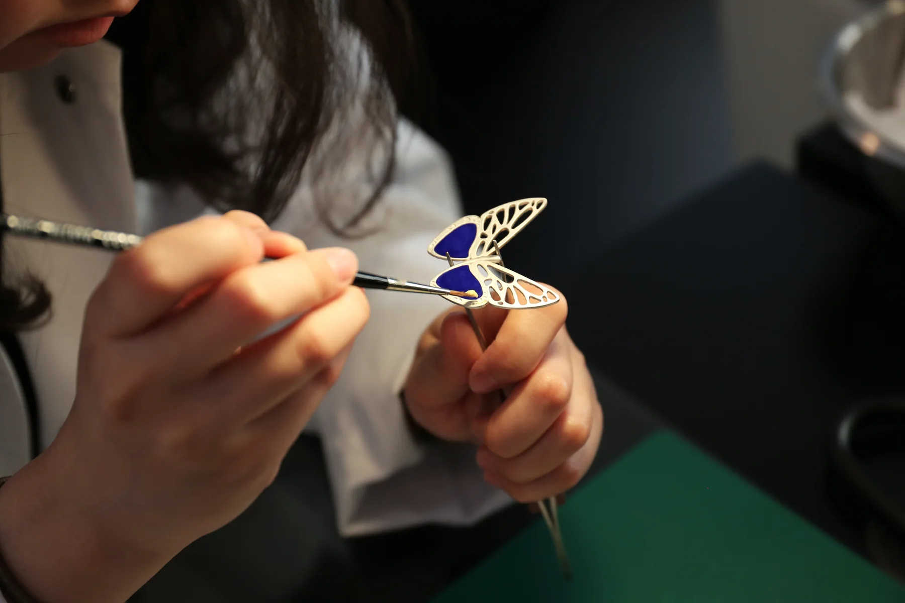 Hand-painting an enamel butterfly during a talk on the art of enameling at L&rsquo;&Eacute;COLE