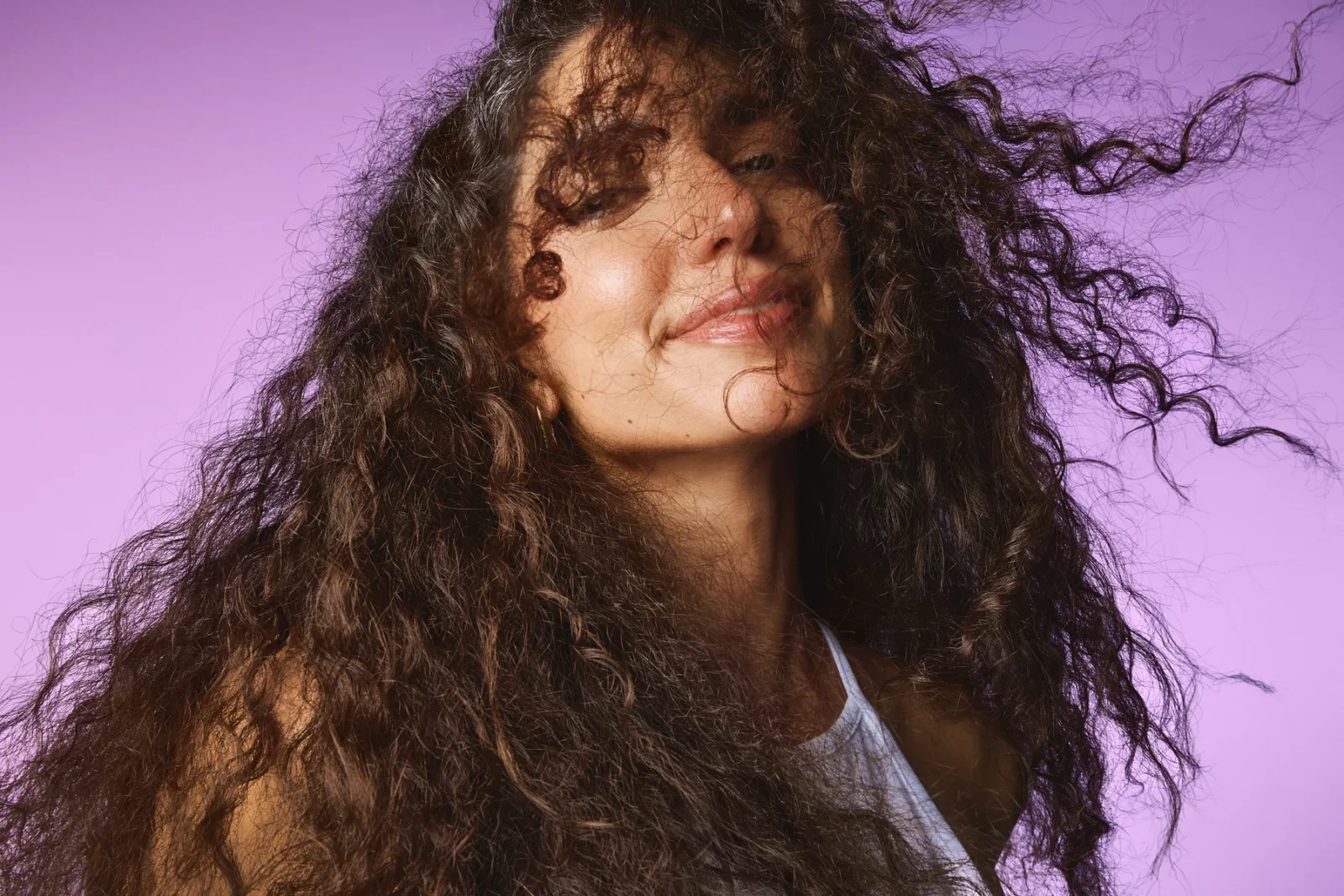 Model with curls smiling on a lilac backdrop, Sephora haircare campaign