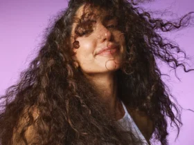 Model with curls smiling on a lilac backdrop, Sephora haircare campaign