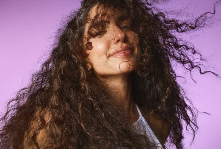 Model with curls smiling on a lilac backdrop, Sephora haircare campaign