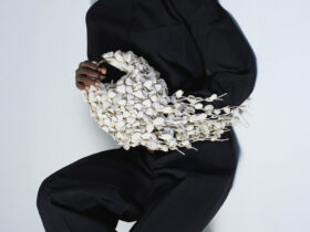 The Polène Béri Lif in Porcelain, held against a black look, its leather-leaf surface in full view