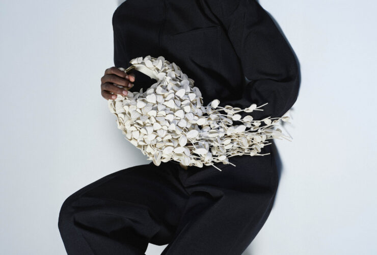 The Polène Béri Lif in Porcelain, held against a black look, its leather-leaf surface in full view