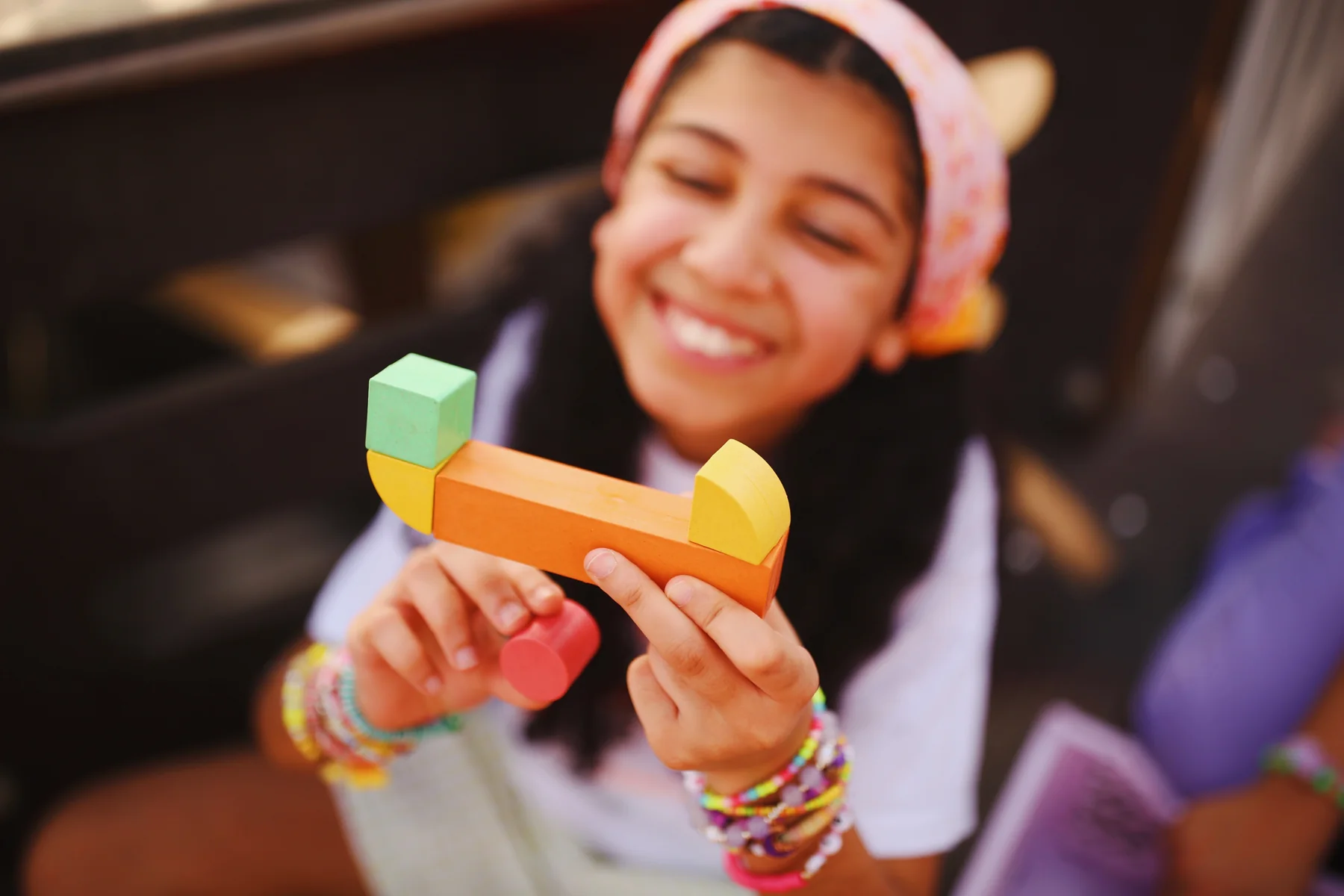 A child beaming behind a spread of colourful Akwan letters