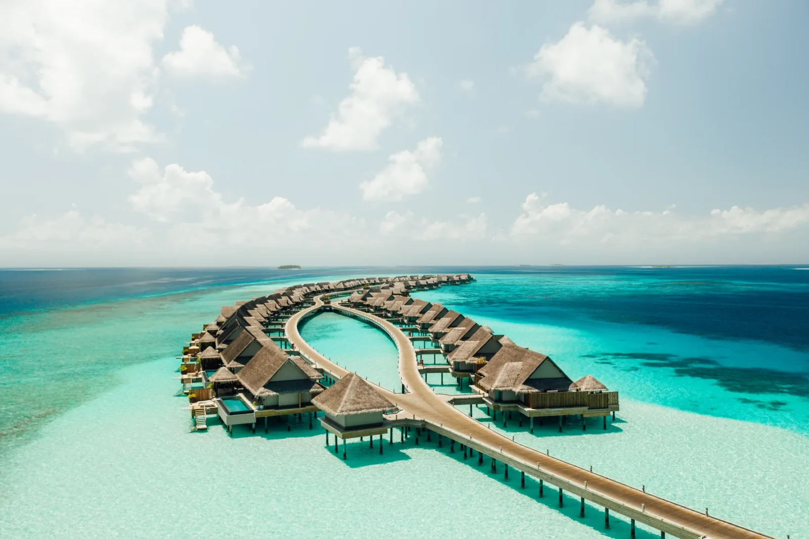 Aerial view of the curved overwater villas at JOALI Maldives