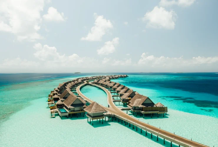 Aerial view of the curved overwater villas at JOALI Maldives