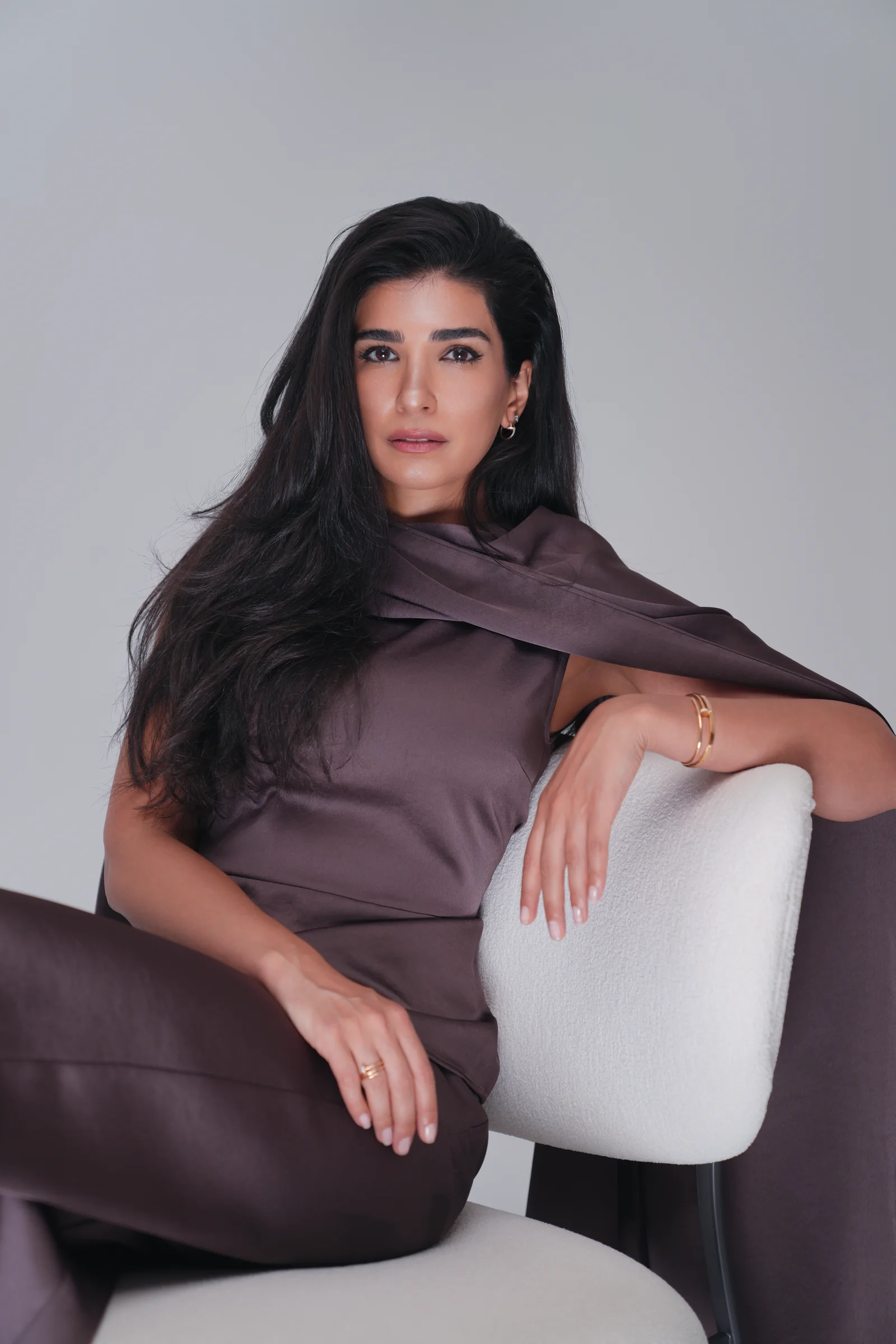 Dr. Noor AlQabandi photographed for Boujeez in a brown satin cape look
