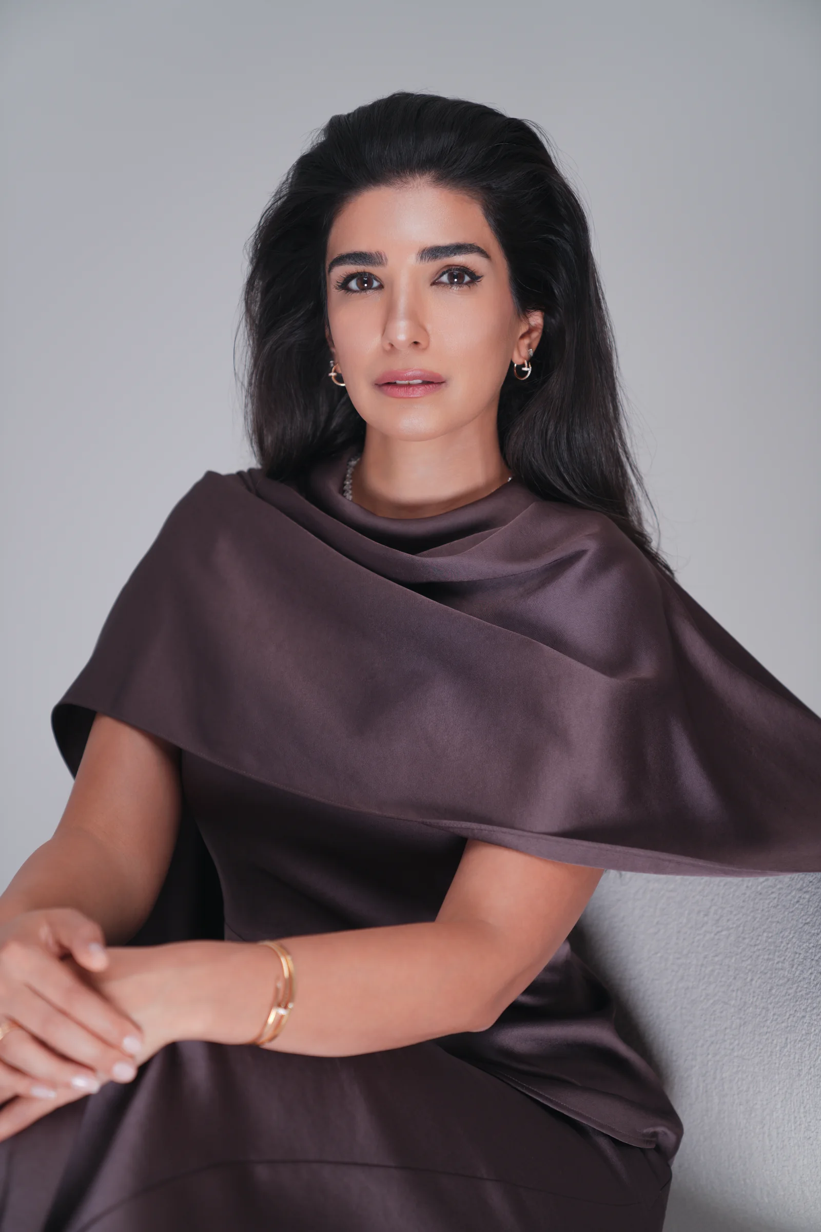 Dr. Noor AlQabandi photographed for Boujeez in a brown satin cape look